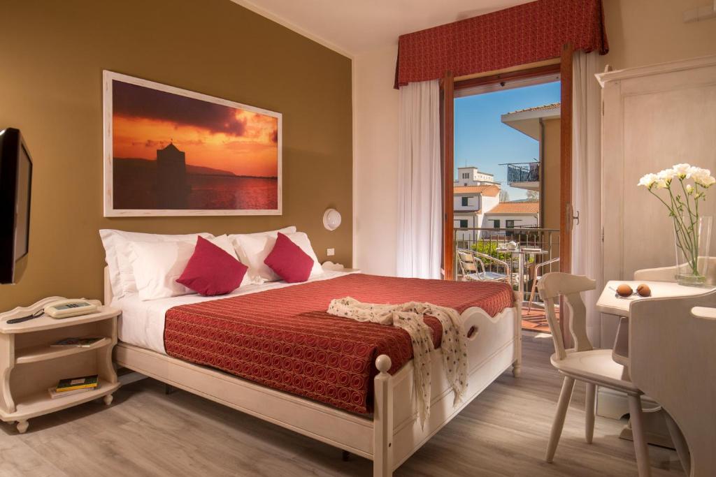 Hotel Corallo في ألبينيا: غرفة نوم بسرير وطاولة ونافذة
