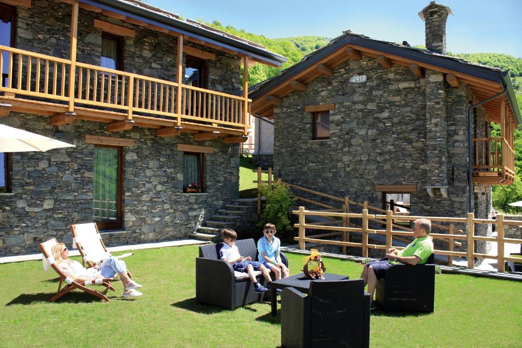 a group of people sitting in chairs in front of a house at Chalets Mongioie in San Giacomo