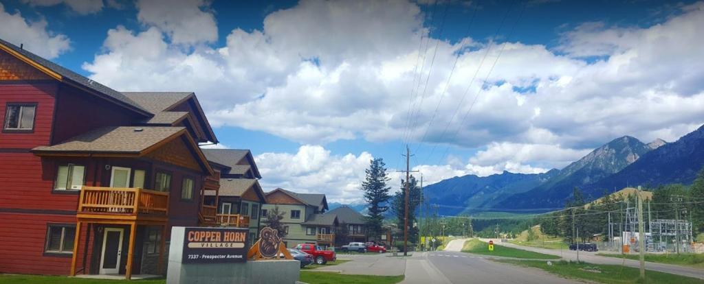 a street in a town with a house and mountains at Mountain View Radium Condo - Copper Horn Village in Radium Hot Springs