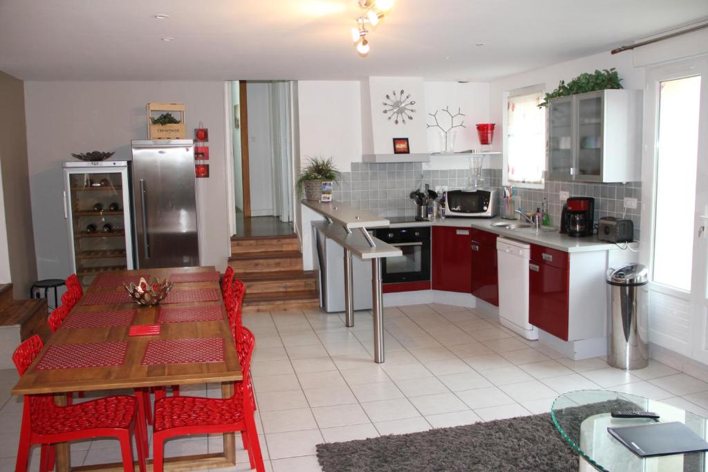 une cuisine avec des placards rouges et une table avec des chaises rouges dans l'établissement Gîte Villa Louis Victor, à Villers-sous-Châtillon