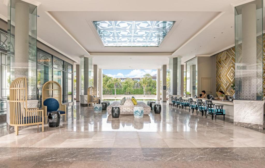 A bright marble lobby opens onto greenery beneath a patterned skylight.