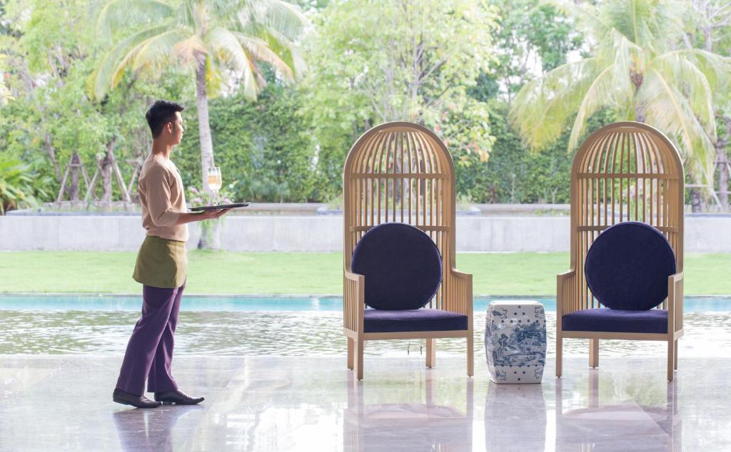 A staff member stands with a laptop beside two distinctive lobby chairs.