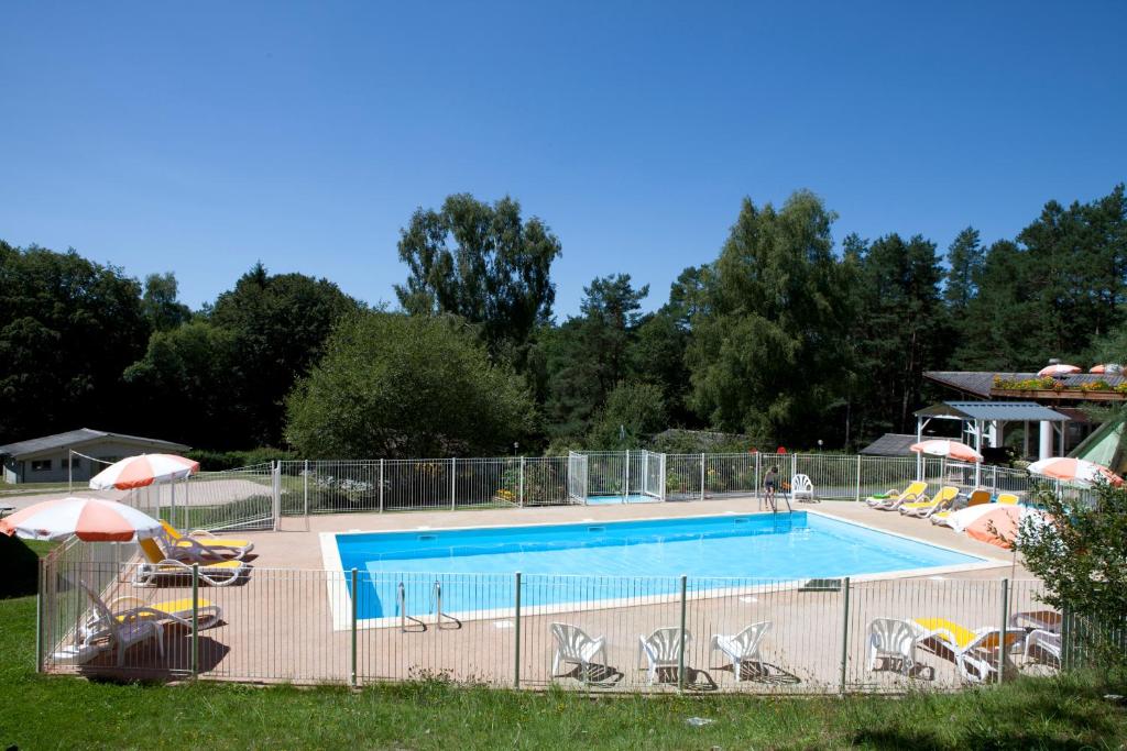 a large swimming pool with chairs and umbrellas at VVF Haute Dordogne in Neuvic