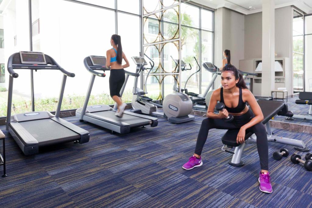 A bright fitness room centered on treadmills, cross-training equipment and free weights.