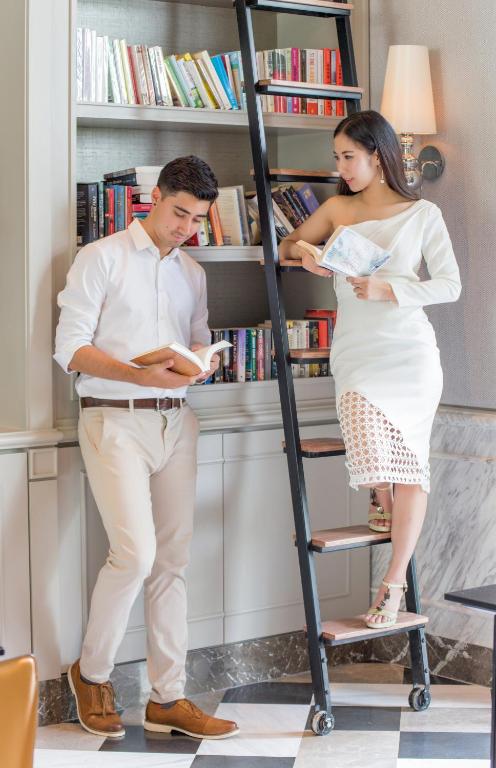 A styled library corner shows two people browsing books beside a rolling ladder.