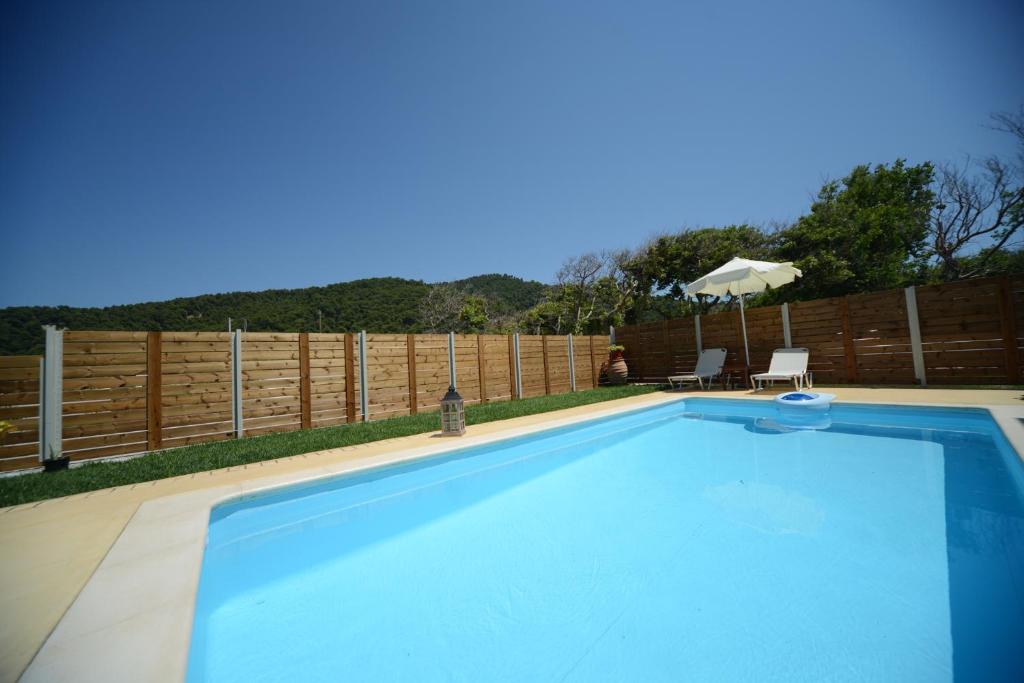 a swimming pool in a backyard with a wooden fence at Aselinos Suites in Koukounaries