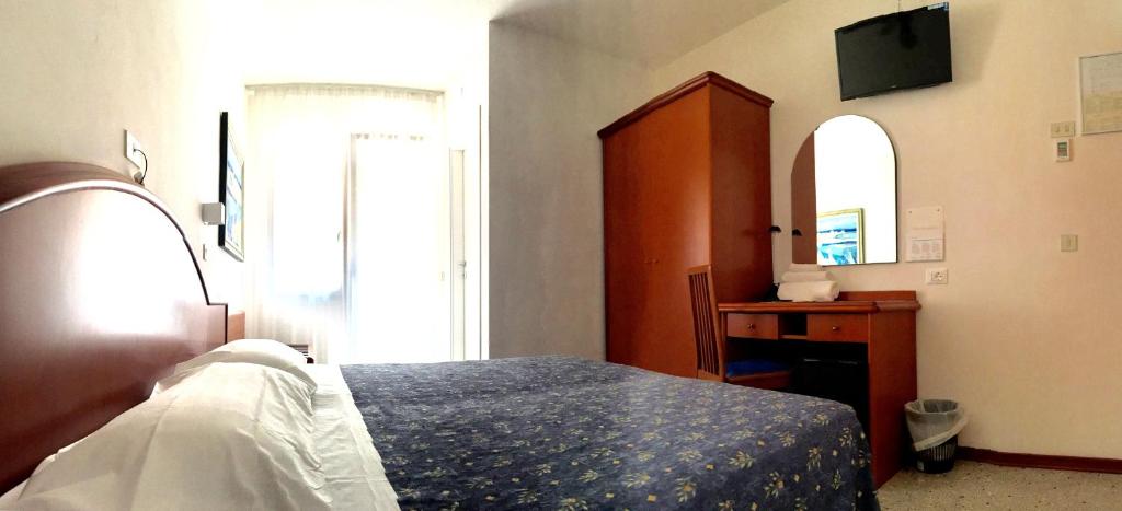 um quarto com uma cama, uma cómoda e um espelho em Hotel Villa Candia em Lignano Sabbiadoro