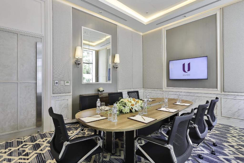 A compact boardroom with a presentation screen and a single oval table.