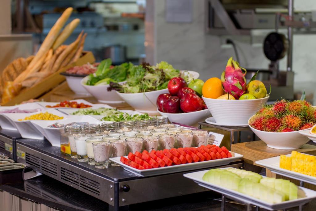 A colourful breakfast station offers fruit, yoghurt, juices, salad greens, and breadsticks.