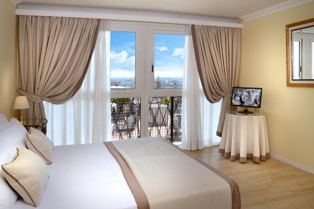 モンテカティーニ・テルメにあるAmbasciatori Palaceのベッドルーム(大きなベッド1台、大きな窓付)