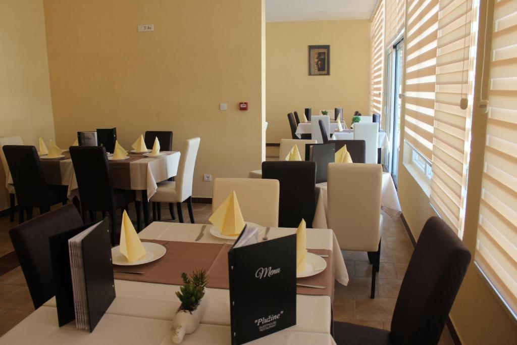 una sala da pranzo con tavoli, sedie bianche e cercapersone di Guesthouse Eko Piva a Plužine