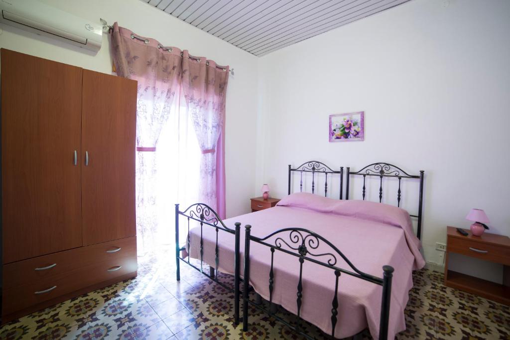 a bedroom with a bed with pink sheets and a window at Largo Madonna in Trapani