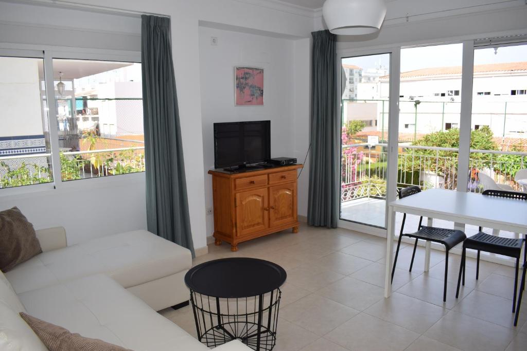 a living room with a white couch and a table with a tv at El Jardin BeNerja in Nerja