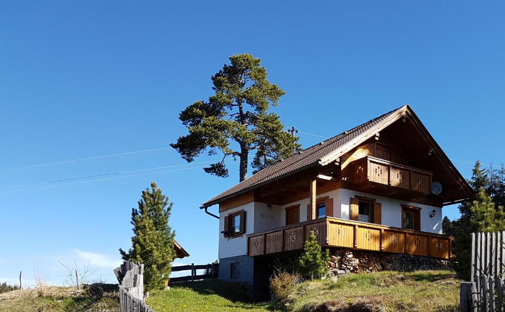 ein Haus auf einem Hügel mit einem Baum im Hintergrund in der Unterkunft Almhütte in Kärnten in Goding