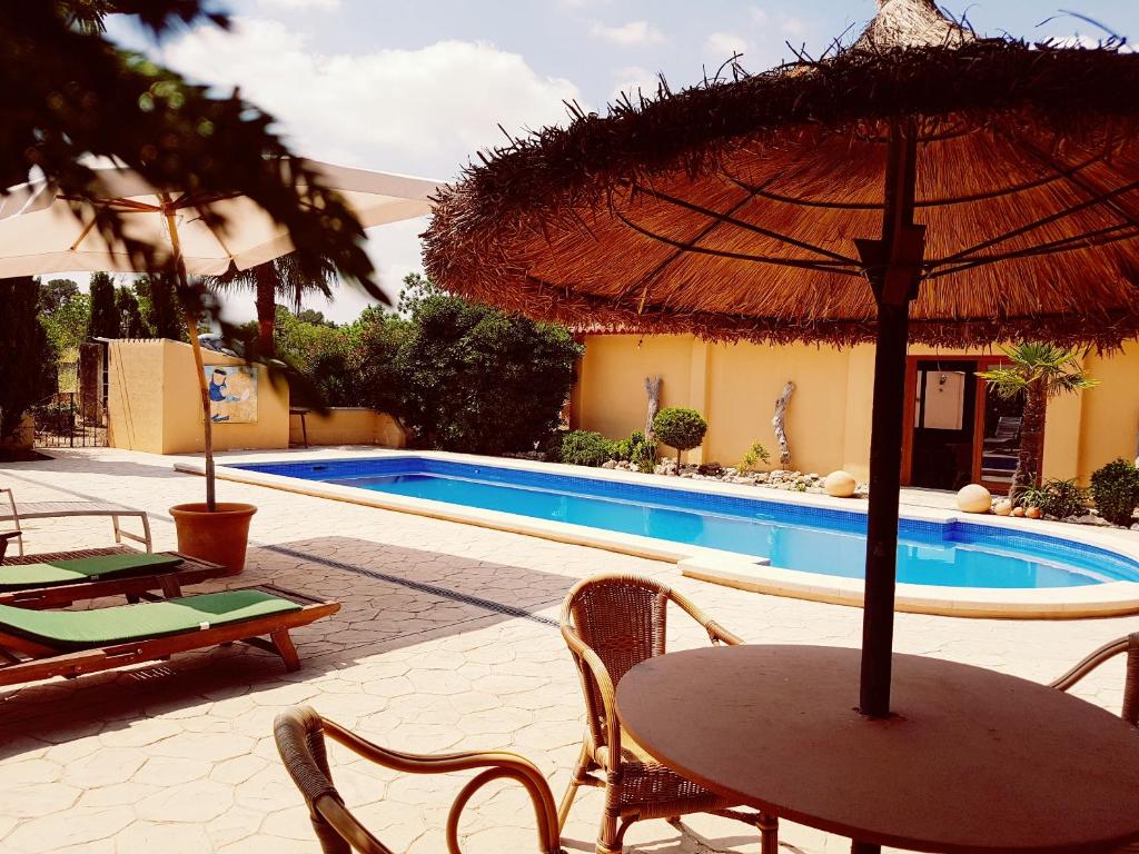 uma mesa com um guarda-sol ao lado de uma piscina em Finca Caballo Blanco em Montuiri
