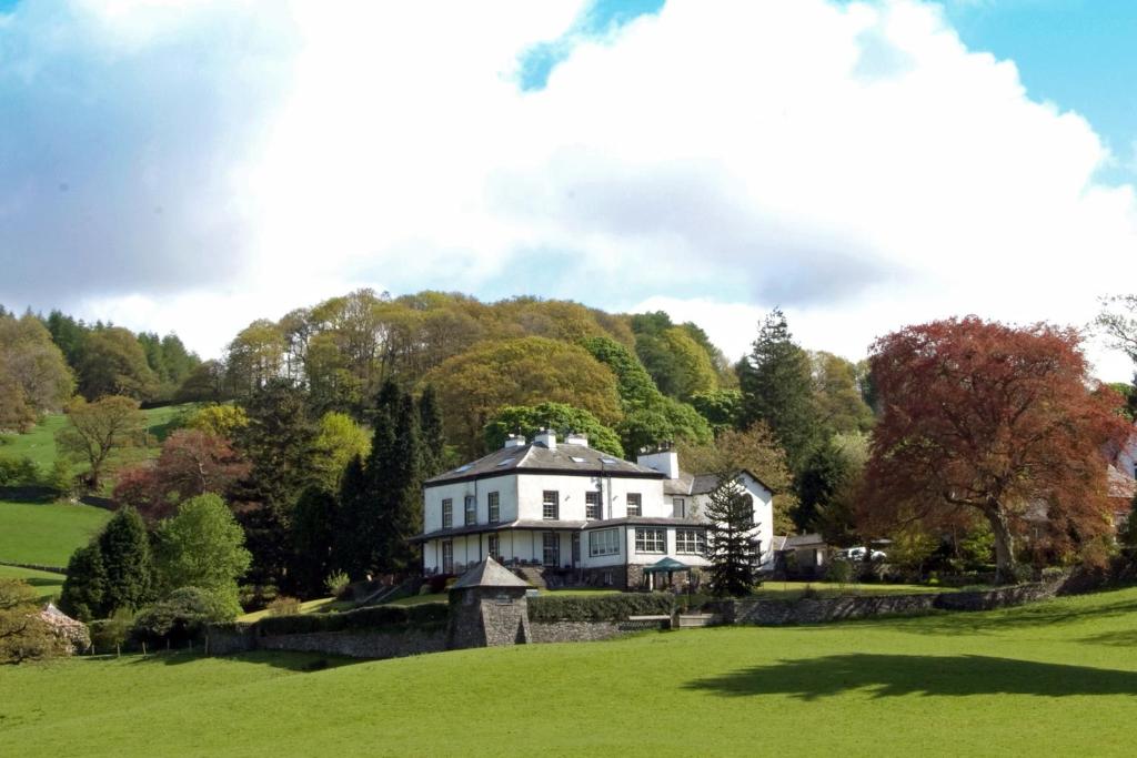 een groot wit huis in een groen veld bij Ees Wyke Country House in Near Sawrey