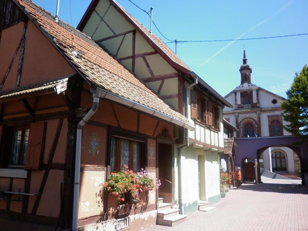 an old building with a church in the background at Gites Petermann in Marckolsheim