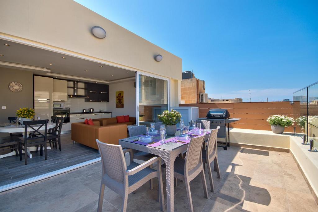 a patio with a table and chairs on a balcony at Valletta Luxe 3-Bedroom Duplex Penthouse with Sea View Terrace and Jacuzzi in Valletta