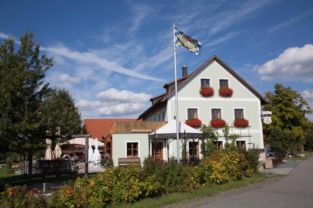 a white building with a flag on top of it at Scheidlerhof in Theisseil