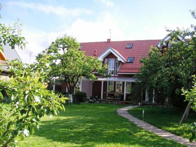 ein Haus mit rotem Dach auf einem grünen Hof in der Unterkunft Apartamentai Obelynė in Palanga