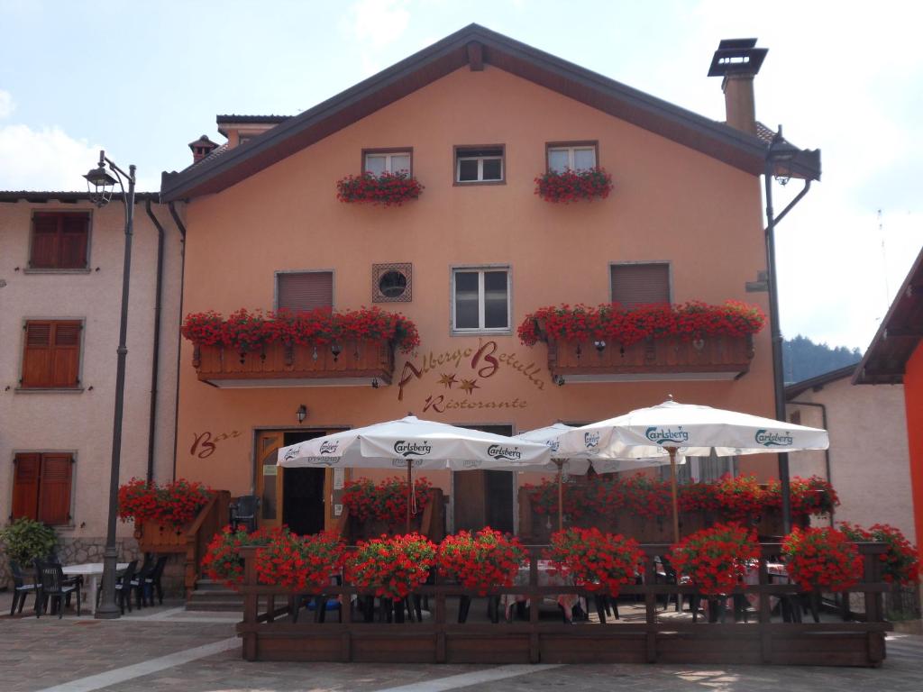 a building with umbrellas and flowers in front of it at Albergo Betulla in Onore