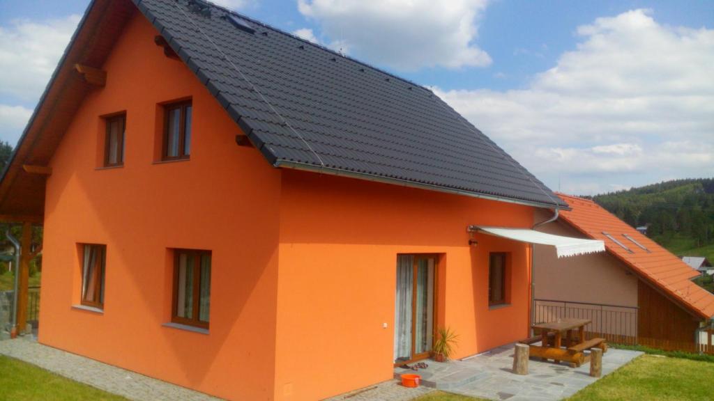 ein orangefarbenes Haus mit schwarzem Dach in der Unterkunft Holiday Home U Fišerů in Kašperské Hory