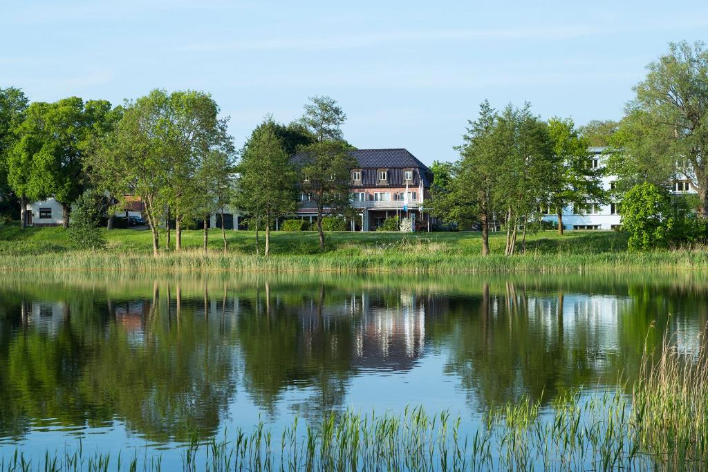 a house is reflected in the water of a lake at Hotel am See in Grevesmühlen