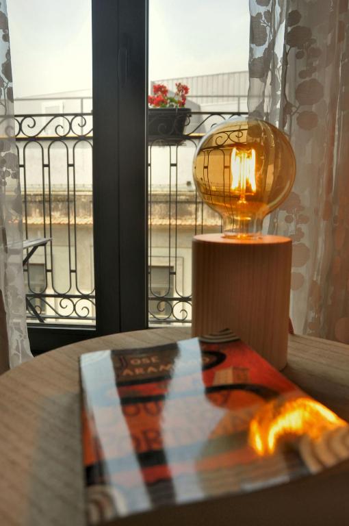 a book on a table with a lamp and a window at PicPorto Apartment in Porto