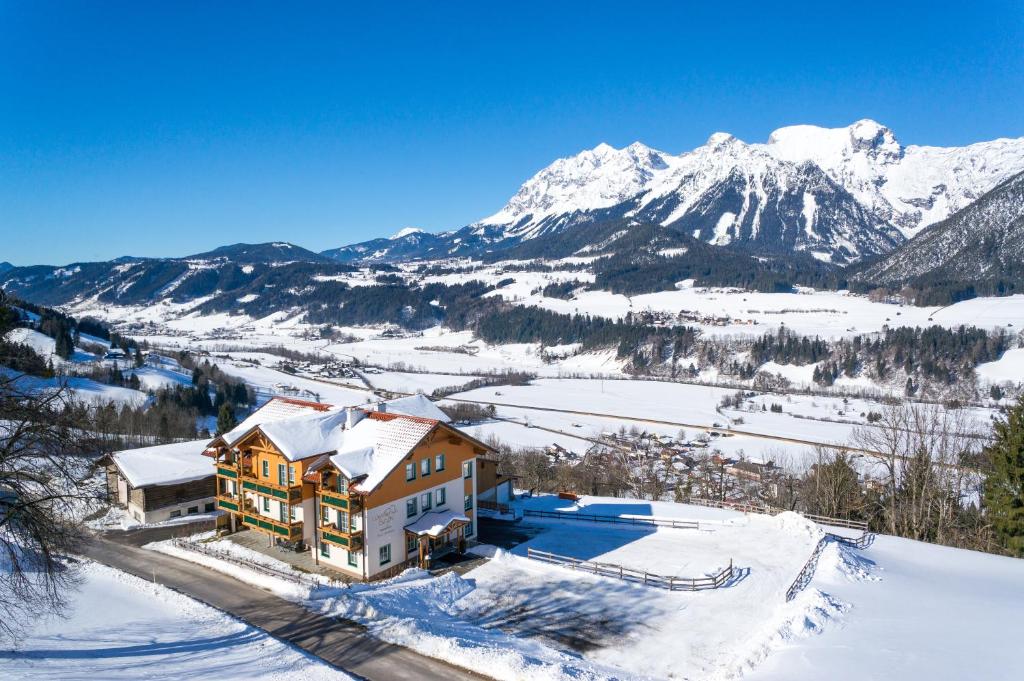 a house in the snow with mountains in the background at Landhaus Birgit in Haus im Ennstal