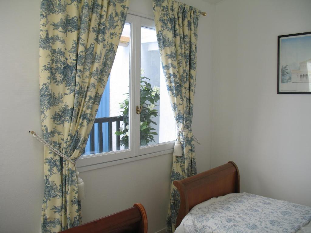 a bedroom with a window with curtains and a bed at Domus Dulcis in Ribérac