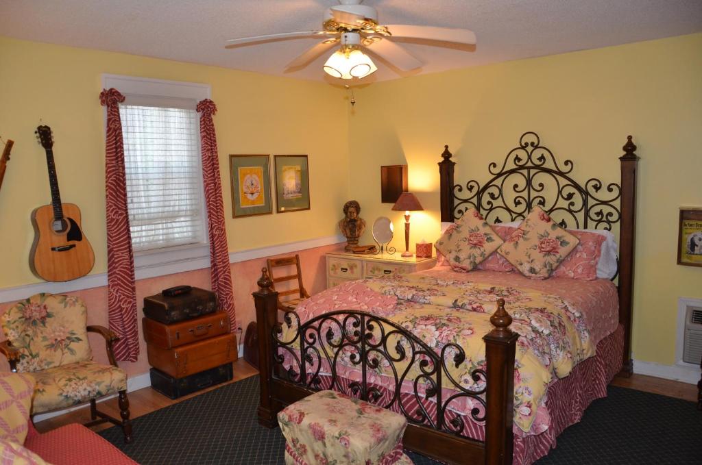 ein Schlafzimmer mit einem Bett, einem Ventilator und einer Gitarre in der Unterkunft Garden Walk Inn in Lookout Mountain