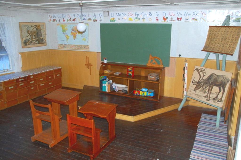 ein Klassenzimmer mit einem Tisch, Stühlen und einer Tafel in der Unterkunft Ljungås Gamla Skola in Askersund