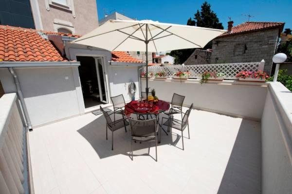 a table and chairs with an umbrella on a balcony at Apartment Piccolo Paradiso in Split