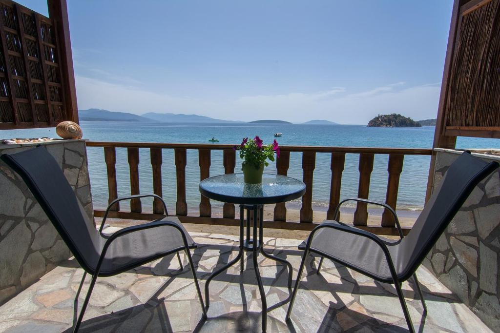 uma mesa e cadeiras numa varanda com o oceano em Poseidon Apartments em Tolo