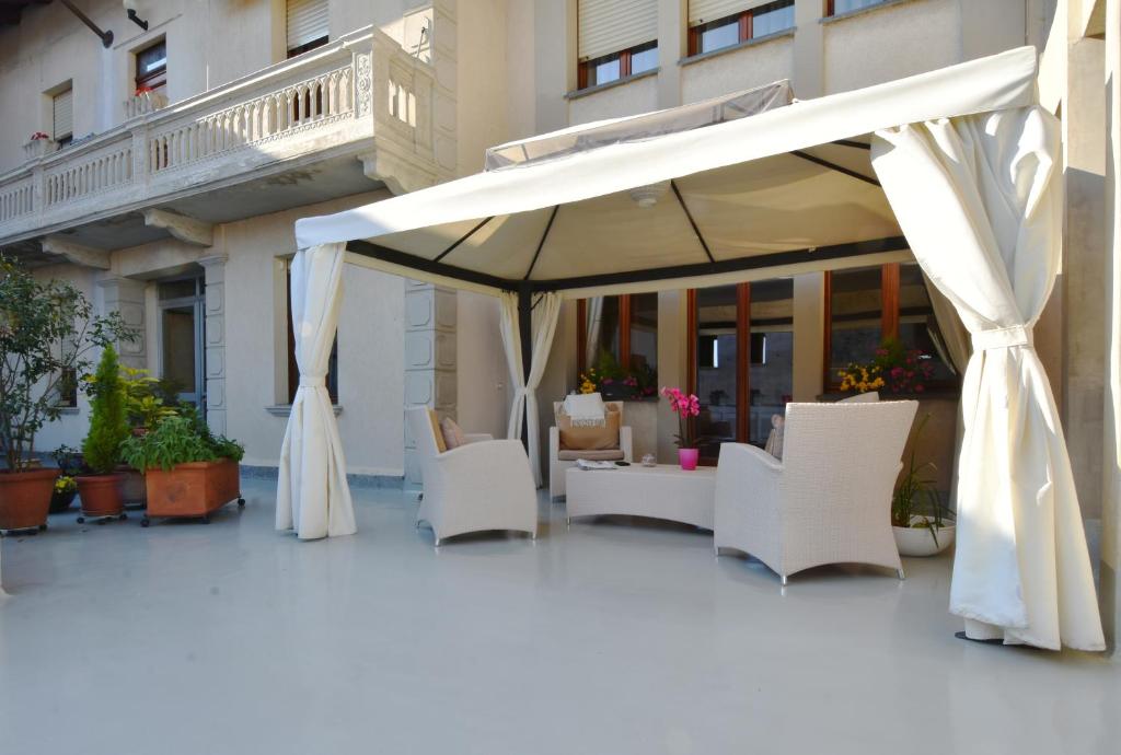 un patio con sillas blancas y una sombrilla en Il Terrazzo B&B, en Romagnano Sesia