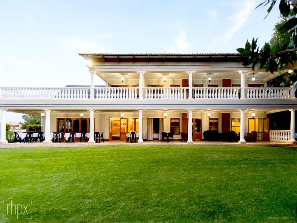 a large white house with a green lawn at OR Tambo Guest House in Kempton Park