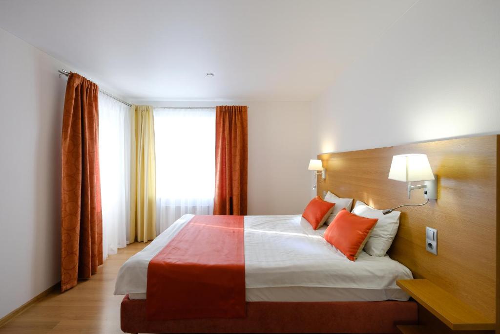 トムスクにあるApart Petrovskie on Sovetskaya 90の大きなベッド(オレンジ色の枕付)が備わる客室です。