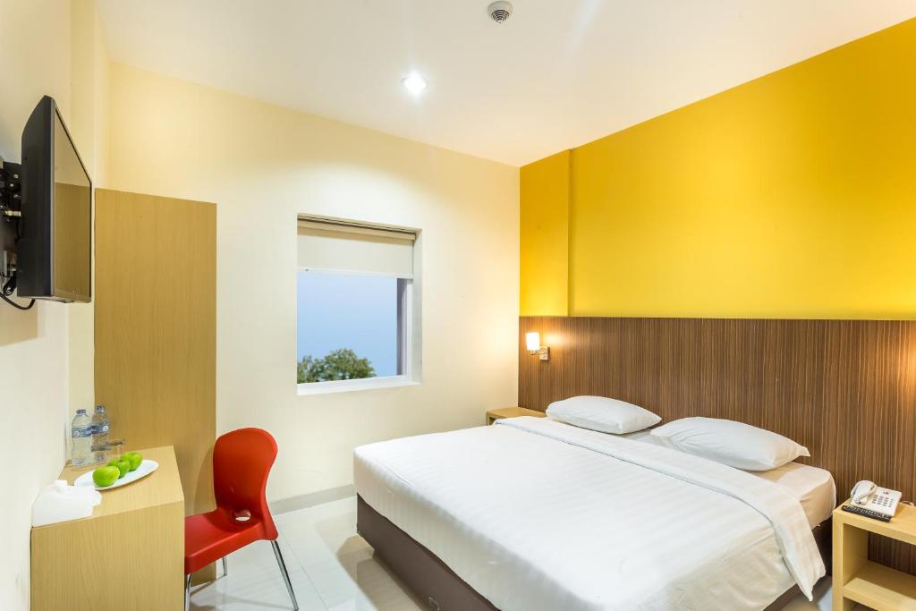 a bedroom with a bed and a yellow wall at Astera Hotel Bintaro in Serpong