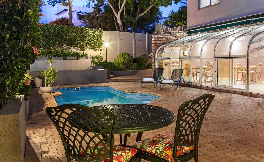 um pátio com uma mesa e cadeiras ao lado de uma piscina em Maroela House Guest Accommodation em Bellville