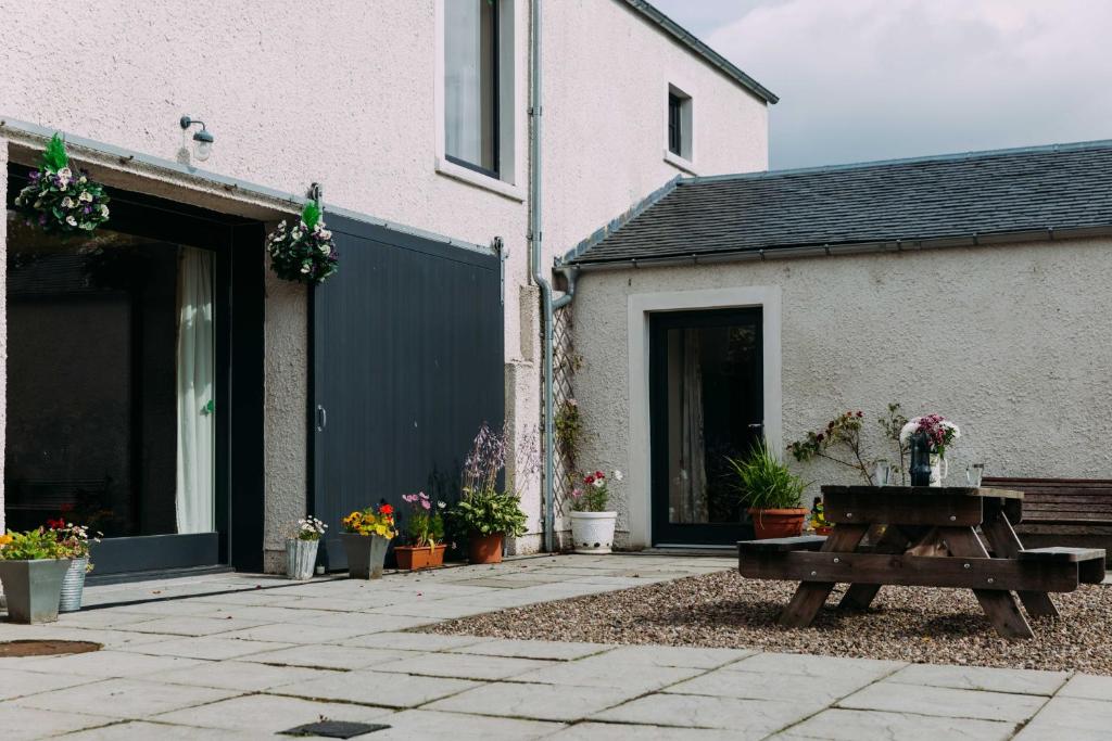 un patio con un banco de madera frente a una casa en Incheoch Farm Granary en Alyth