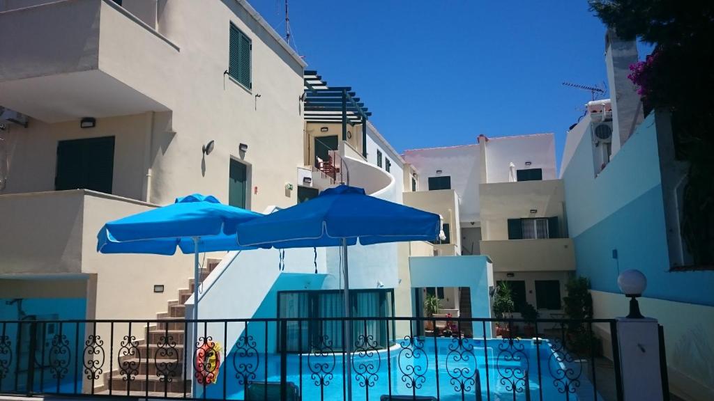 two blue umbrellas on a balcony in front of buildings at 9 Muses in Elafonisos