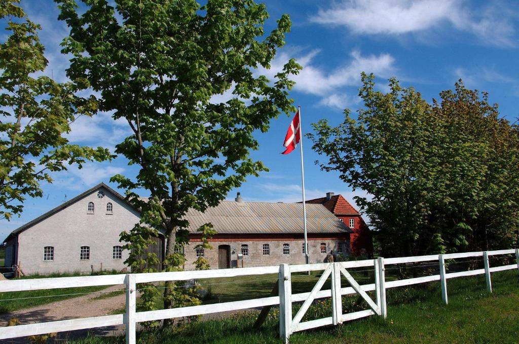 einen weißen Zaun und eine Flagge vor einem weißen Haus in der Unterkunft Nordkap Farm Holiday & Hostel in Bindslev