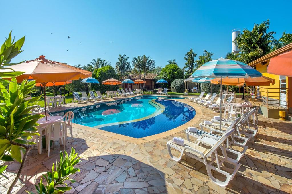 a swimming pool with white chairs and umbrellas at Pousada Paiol in Atibaia