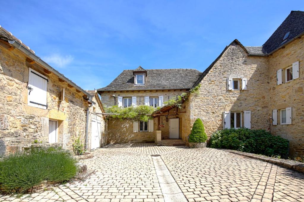 uma antiga casa de pedra com uma entrada de calçada em La Source Gilhodes em Castelnau-de-Mandailles
