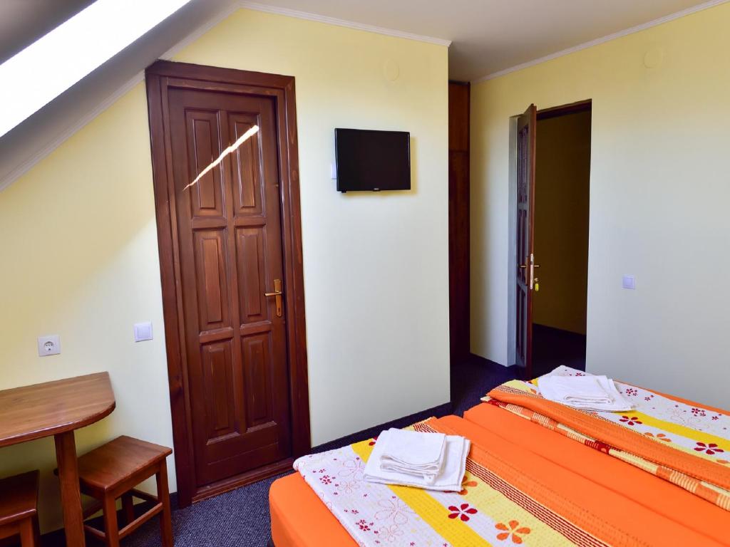 a bedroom with two beds and a table and a door at Gyongyvirag Panzio (Pensiunea Lacramioara) in Turia