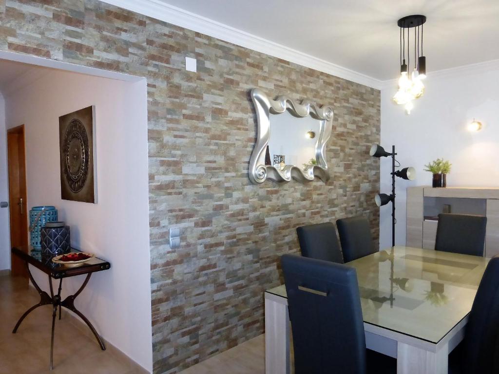 uma sala de jantar com uma mesa de vidro e uma parede de tijolos em Lucas' House em Lagos