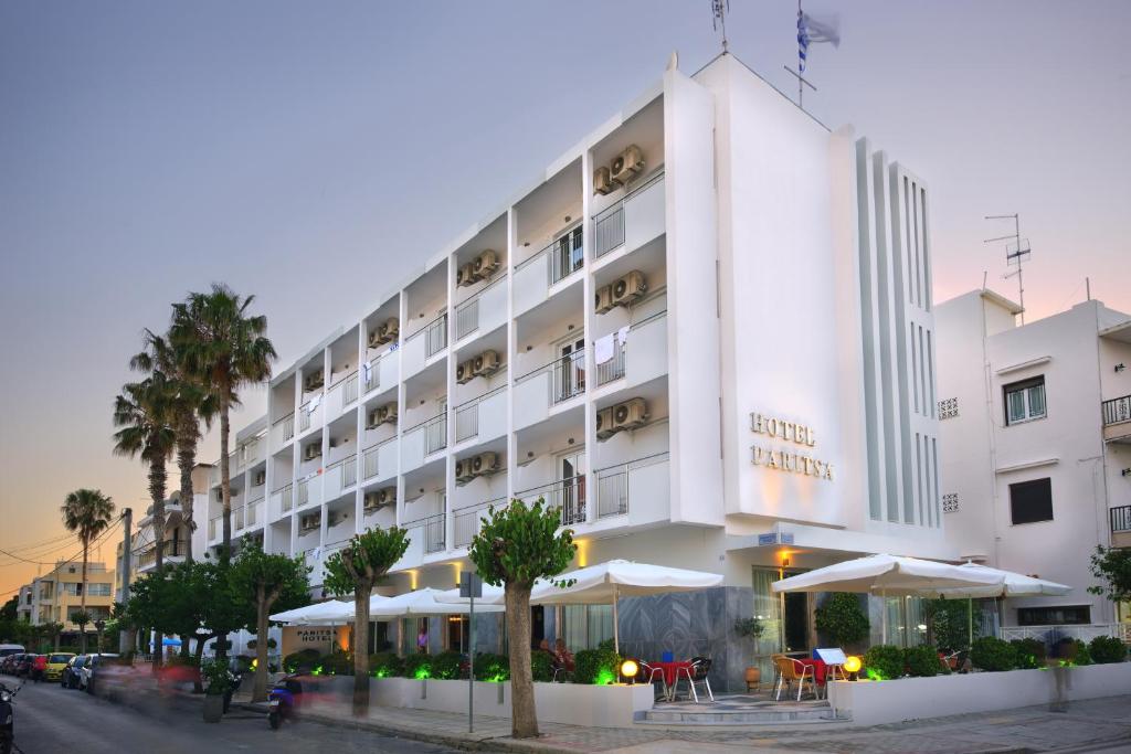 un grande edificio bianco con ombrelloni di fronte di Paritsa Hotel a Città di Kos
