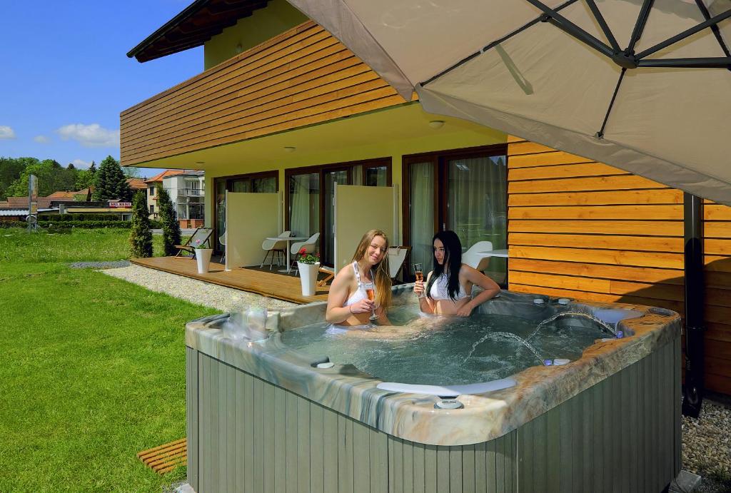 two women sitting in a hot tub in a backyard at AHA Jasná Apartmány in Liptovský Mikuláš