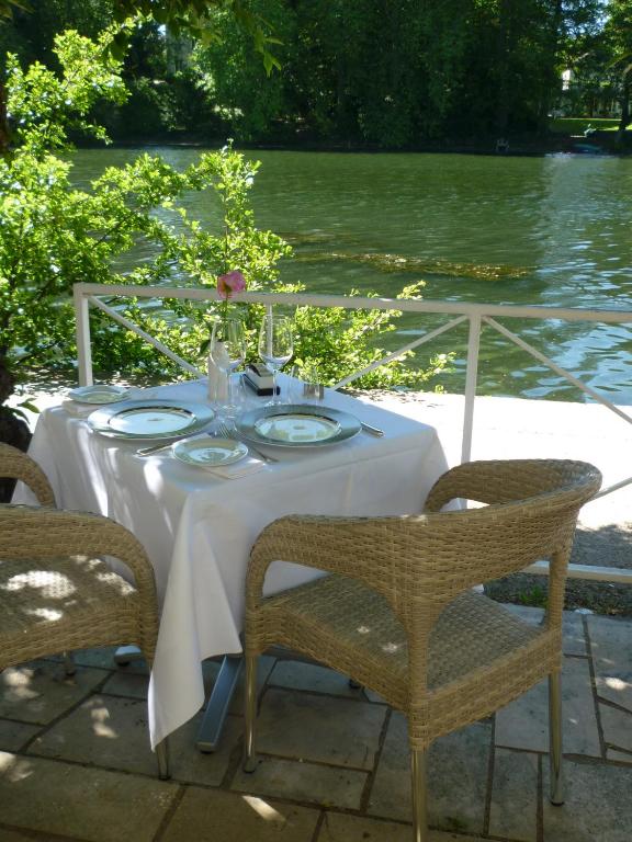 stół z białą tkaniną i krzesłami oraz wodą w obiekcie Hotel Le Rivage w mieście Olivet