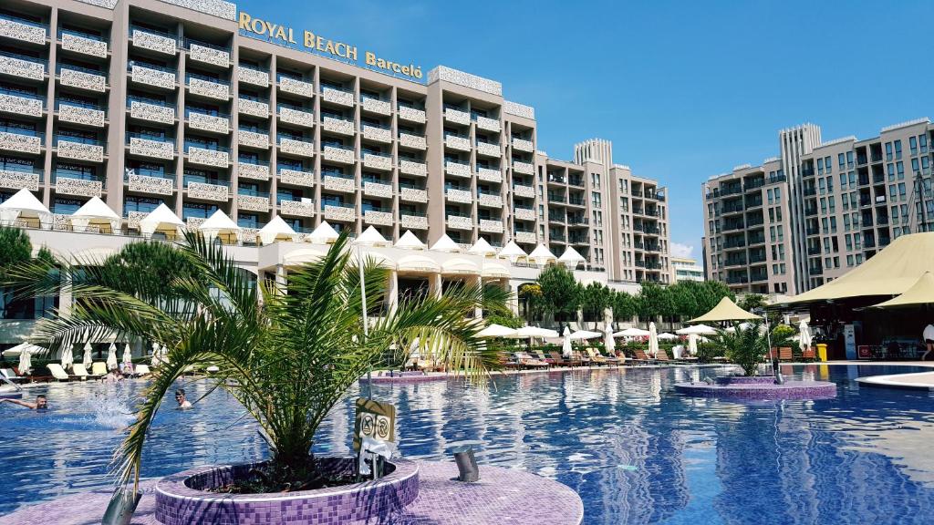una piscina de hotel con una palmera frente a un edificio en Royal Beach Private Apartments, en Sunny Beach